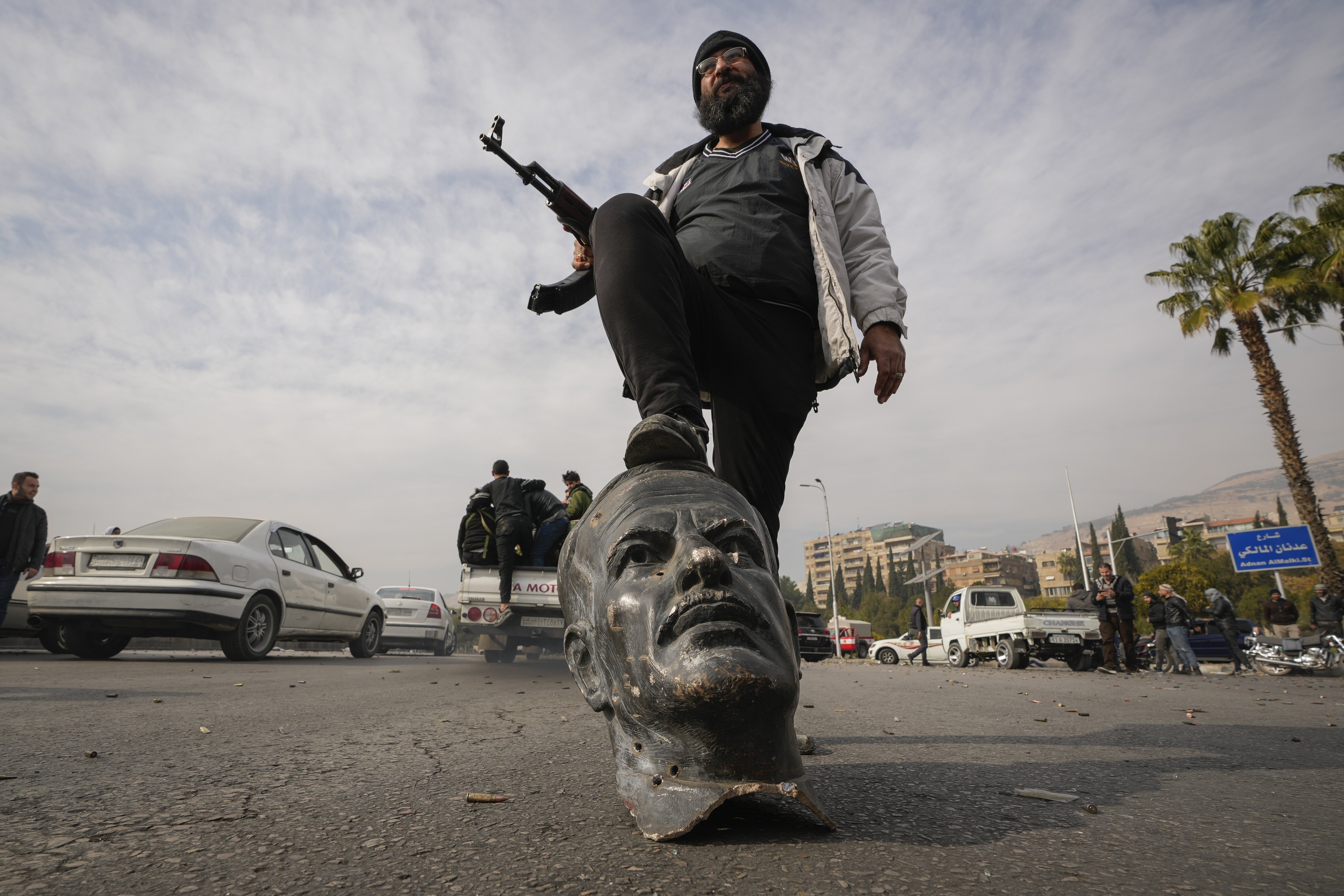 An opposition fighter steps on a broken bust of the late Syrian President Hafez Assad in Damascus, Syria, on Dec. 8, 2024.