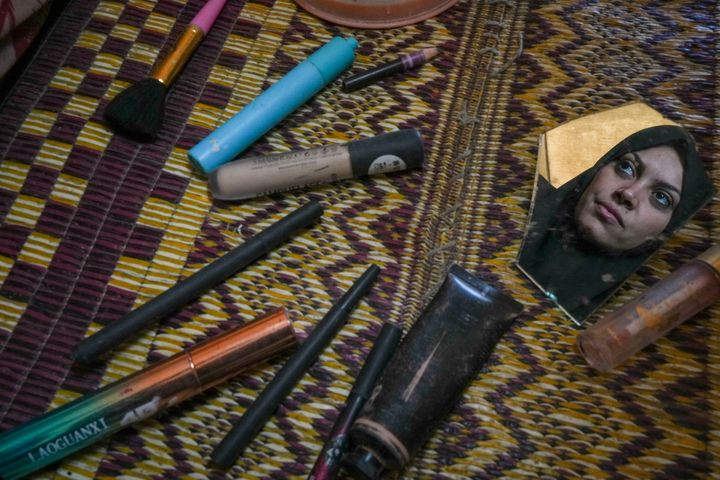 Alaa Hamami gazes into a fragment of a broken mirror as she poses for a portrait beside her deteriorating cosmetics in her tent at a camp for displaced Palestinians in Deir al-Balah, Gaza Strip, on Dec. 18, 2024.