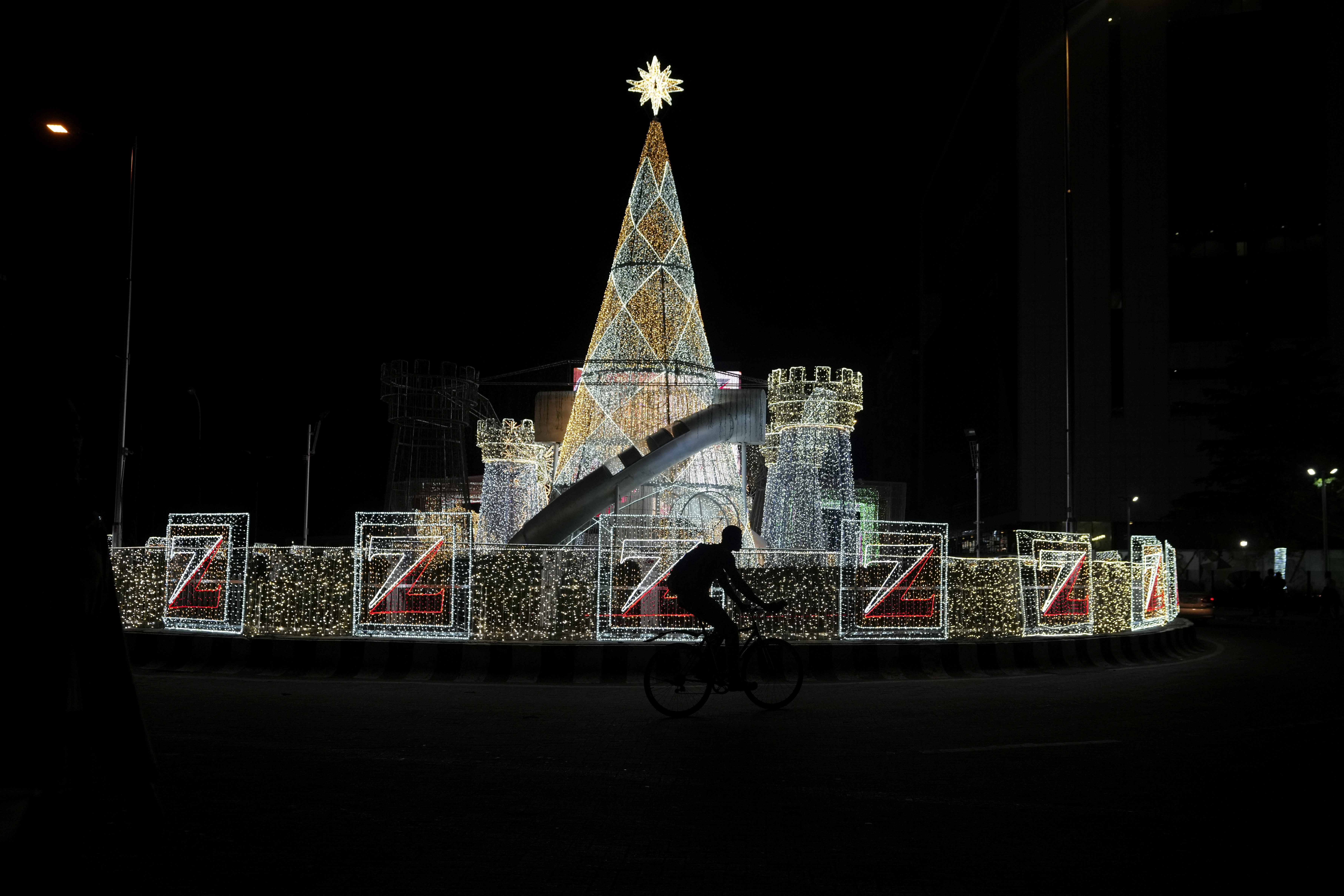 A man rides a bicycle past Christmas decorations on a street in Lagos, Nigeria, Friday, Dec. 20, 2024. (AP Photo/Sunday Alamba)