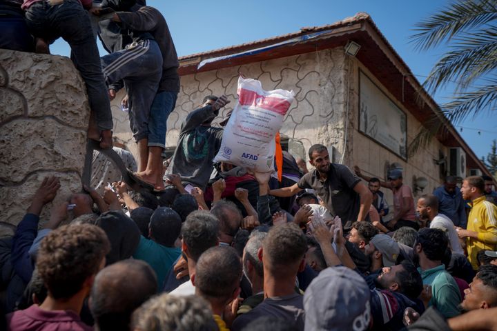 Palestinians gather to receive bags of flour distributed by UNRWA, the U.N. agency helping Palestinian refugees, in Deir al Balah, central Gaza Strip, Saturday, Nov. 2, 2024. (AP Photo/Abdel Kareem Hana)