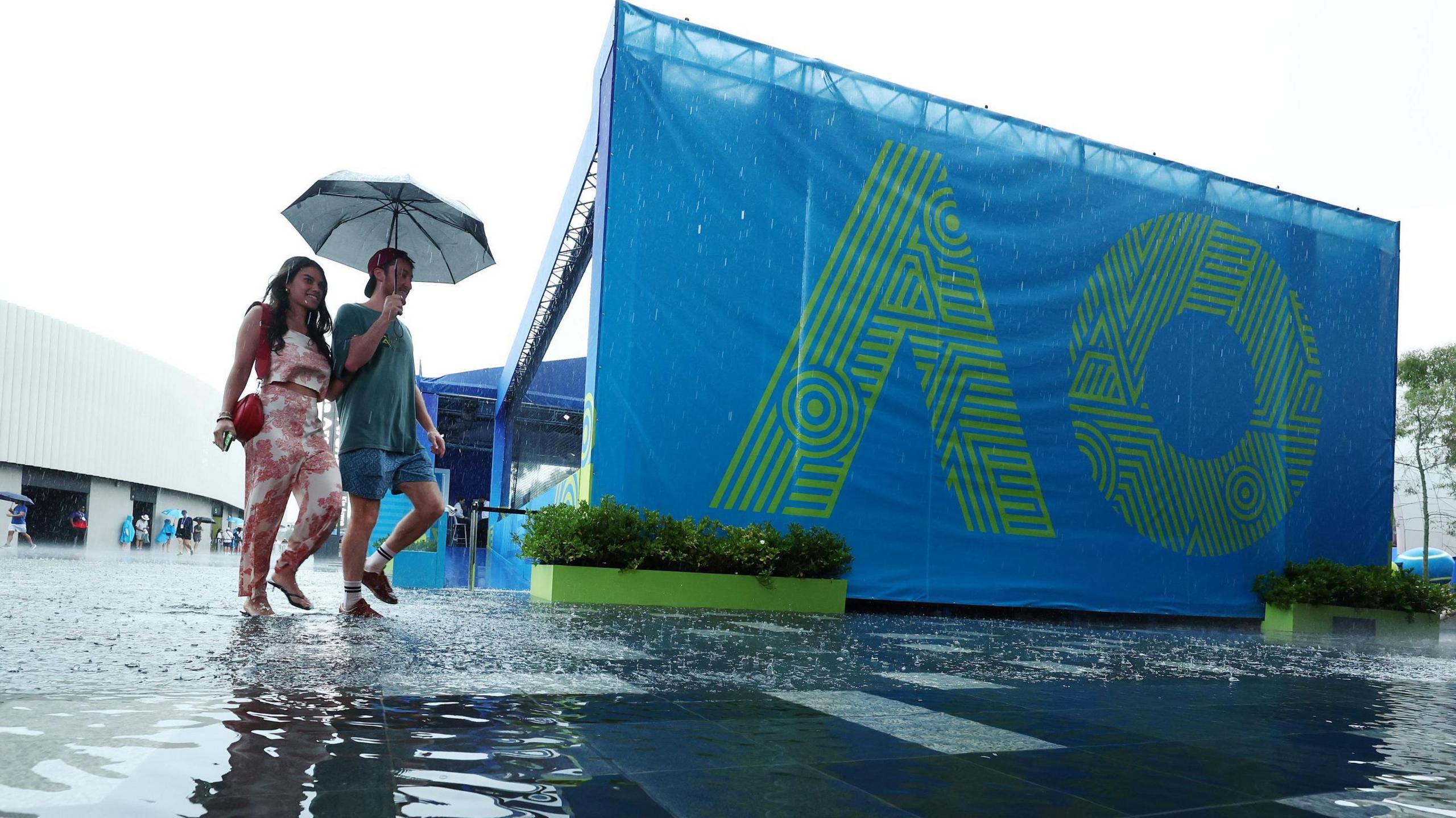 Fans arrive at Melbourne Park under an umbrella