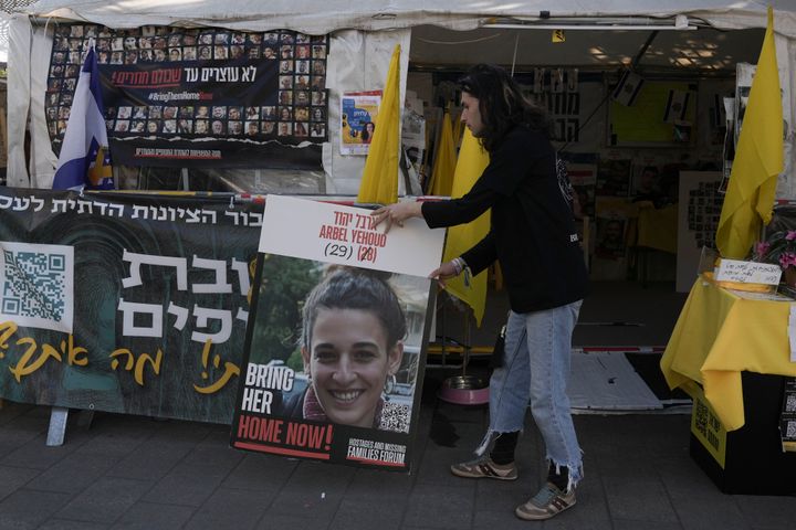 In Jerusalem, a man places a photo of Israeli woman Arbel Yehoud next to a banner in Hebrew demanding the return of hostages held by Hamas in Gaza, on, Monday, Jan. 27, 2025.