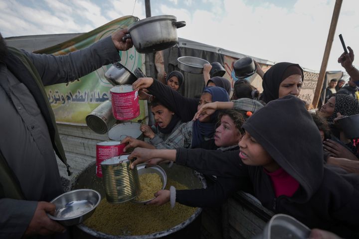 Palestinians struggle to reach for food at a distribution center in Khan Younis, Gaza Strip, Friday, Jan. 9, 2025. (AP Photo/Abdel Kareem Hana)