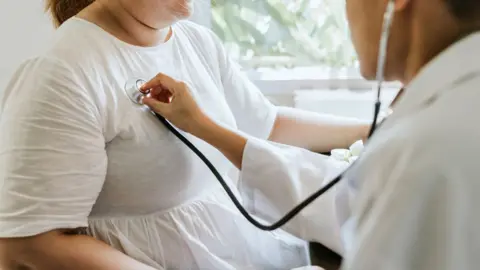 Getty Images A doctor listens to the chest of an overweight lady using a stethoscope