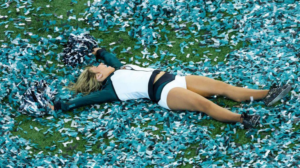 An Eagles cheerleader gets in on the fun, doing a ticker tape angel