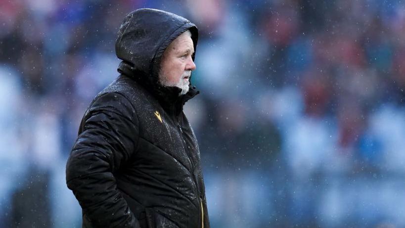 Warren Gatland in black coat in rain