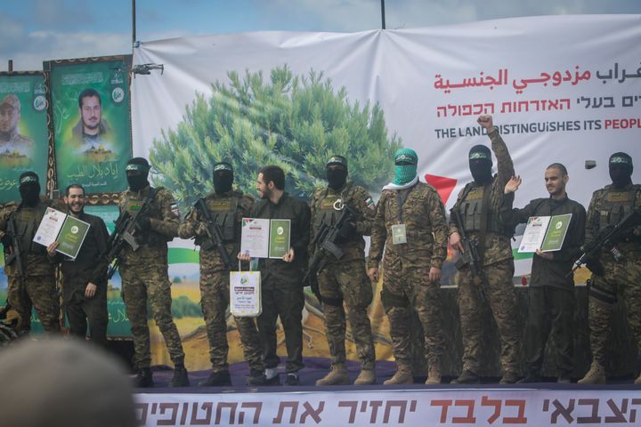 Israeli hostages, from left to right, Eliya Cohen, Omer Shem and Omer Wenkert, show Hamas issued certificates as instructed by militants, before being handed over to the Red Cross in Nuseirat, central Gaza Strip, Saturday, Feb. 22, 2025. (AP Photo/Jehad Alshrafi)