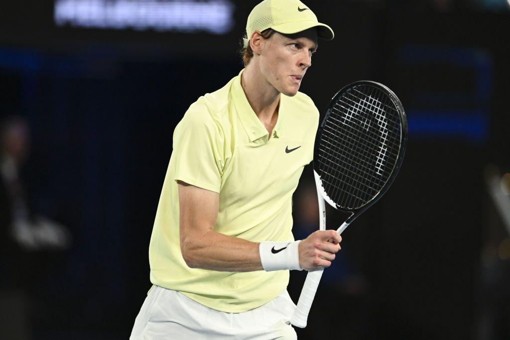 Jannik Sinner holds up a tennis racquet