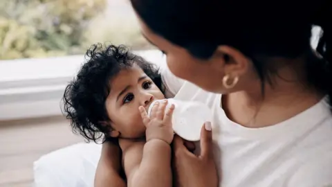 Getty Images A mother feeding her baby bottled milk