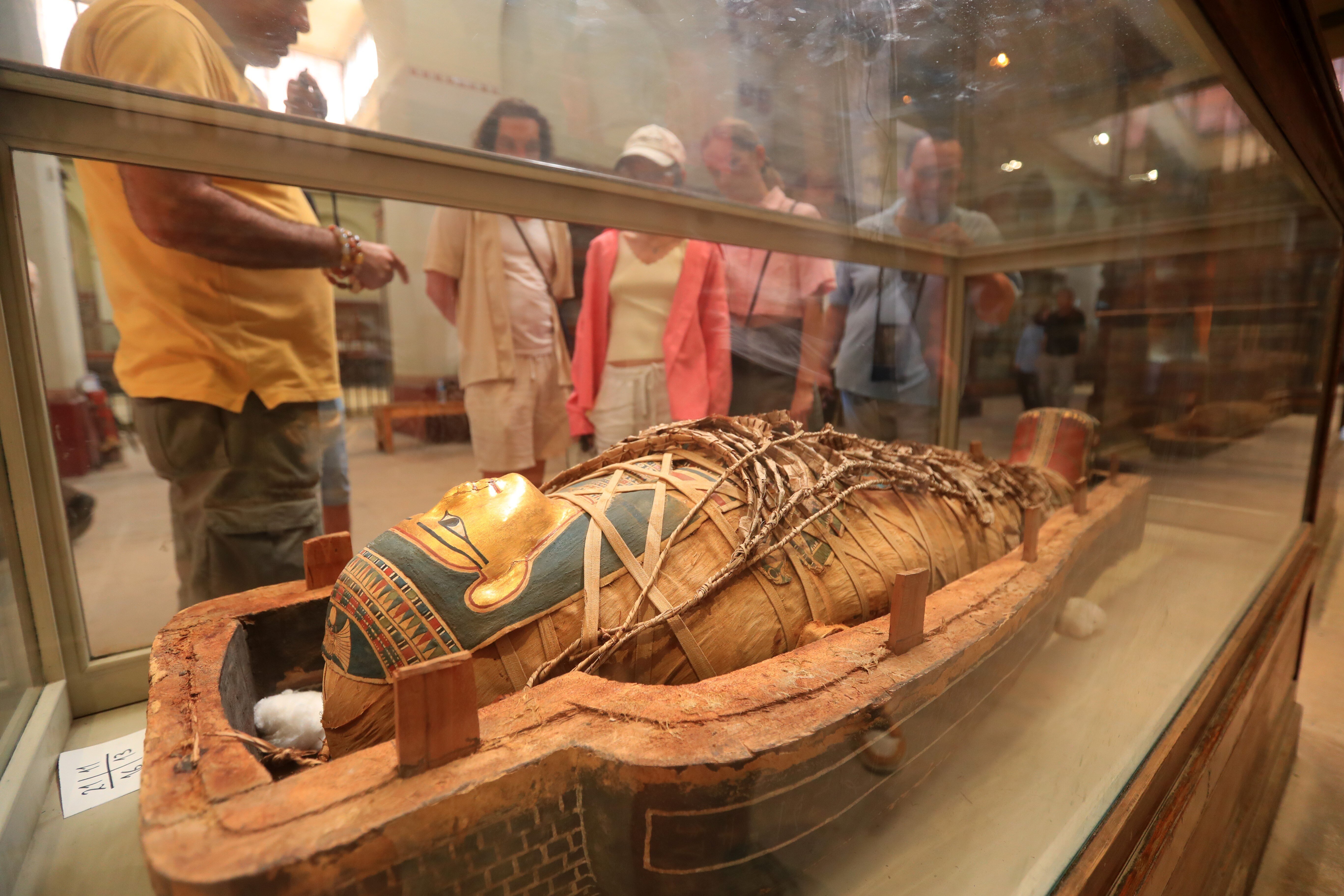 Tourists look at an intact mummy at the Egyptian Museum in Cairo, Egypt.