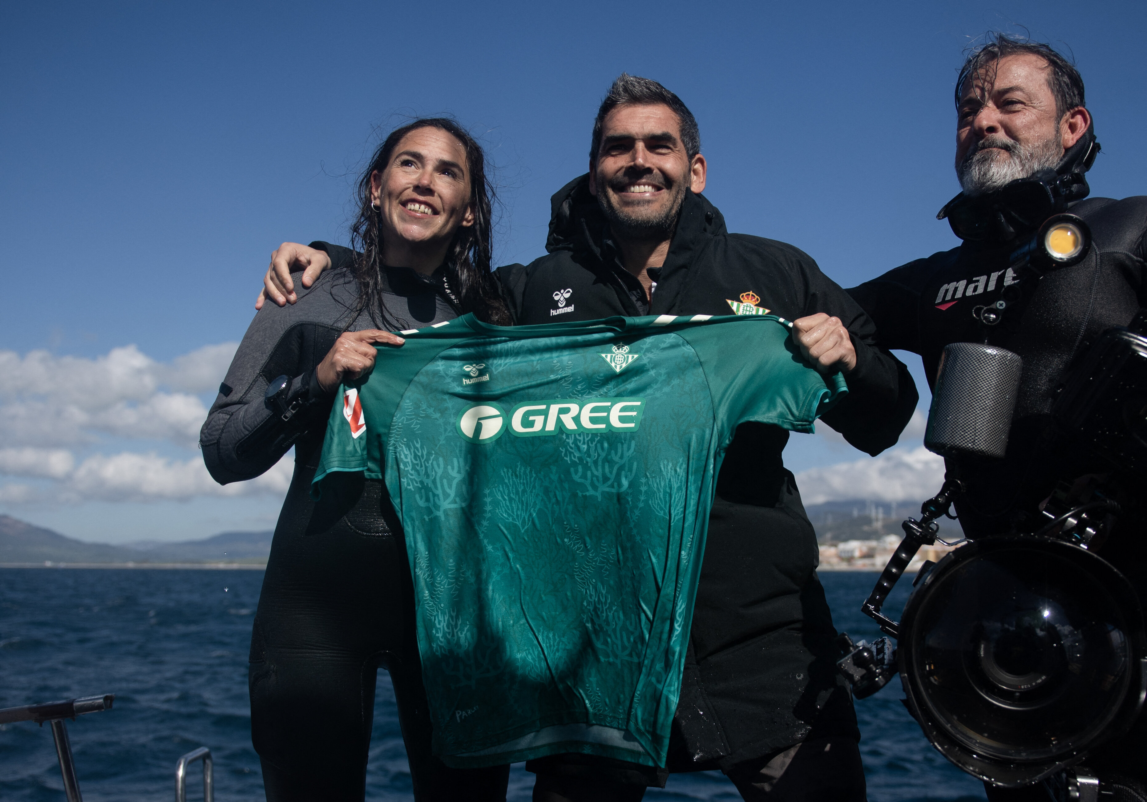 Real Betis foundation director Rafael Muela (center), with divers, holds up a new kit for Spanish Liga team Real Betis Balompie which is made from algae and plastics collected from the bottom of the sea.