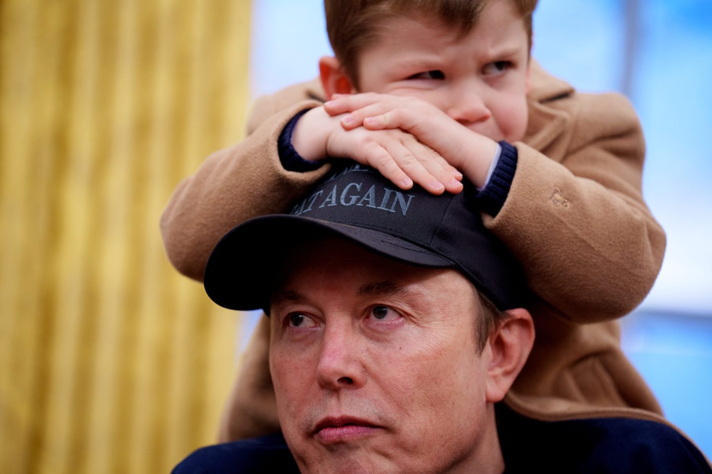 X Musk sits on the shoulders of his father, Tesla and SpaceX CEO Elon Musk, as they join U.S. President Donald Trump for an executive order signing in the Oval Office at the White House on February 11, 2025 in Washington, DC. Trump is to sign an executive order implementing the Department of Government Efficiency's (DOGE) "workforce optimization initiative," which, according to Trump, will encourage agencies to limit hiring and reduce the size of the federal government.