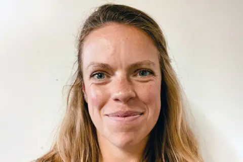 A head and neck shot of Dr Patsie Staite, who is smiling against a white background. She has mousey blonder-brown hair which is half tied up. 