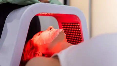 Getty Images Close-up of a woman having LED light facial treatment in beauty salon