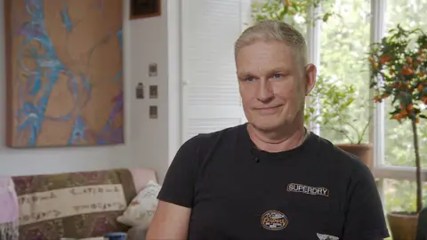 Philip Hurd, a man with light coloured hair wearing a black T-shirt with a Superdry logo